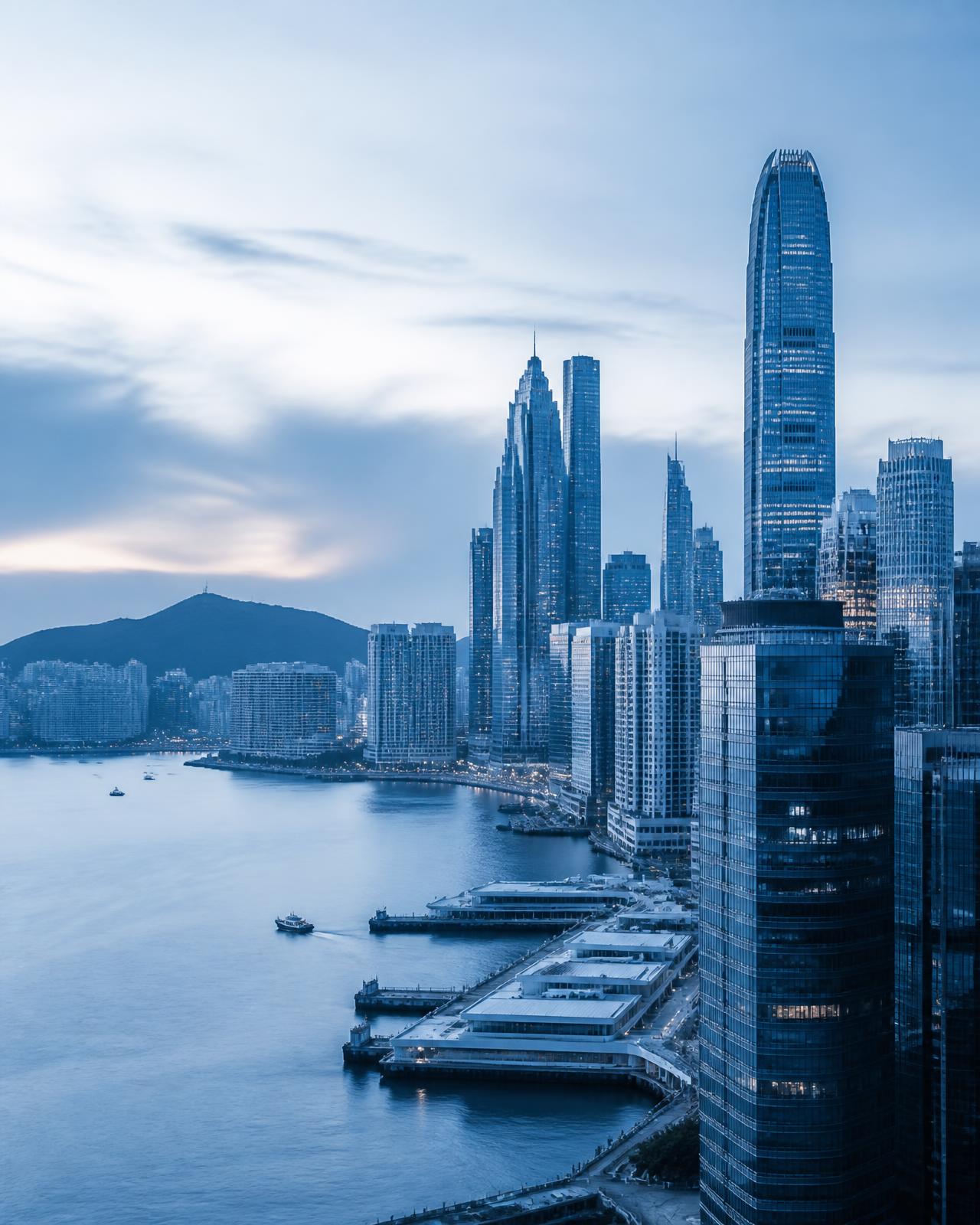 View of a modern urban skyline with glass towers beside a bay, in blue light.